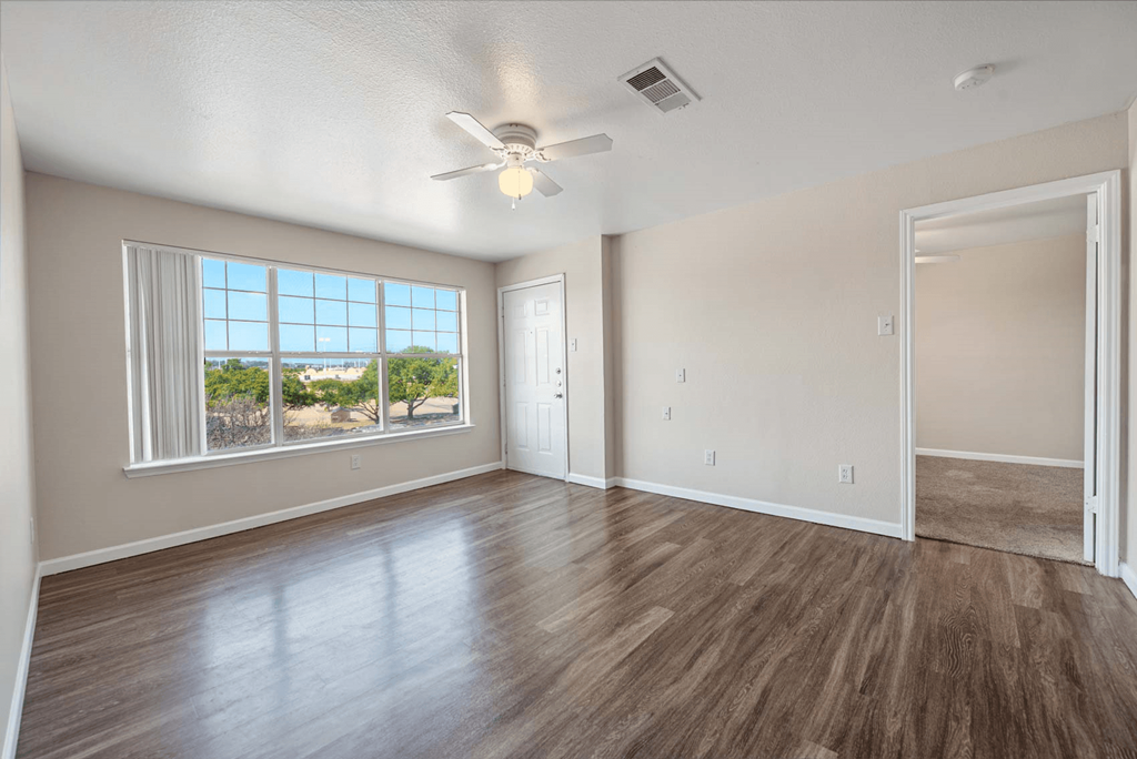 an empty living room with a large window and a ceiling fan  at Collective on Riverside, Austin, Texas